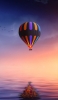 📱海の上を飛ぶ虹色の気球 iPhone 14 Pro 壁紙・待ち受け