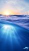 📱綺麗な青い海 光る太陽 iPhone 14 Plus 壁紙・待ち受け
