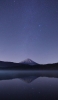 📱夜の銀河と湖に鏡面する山 iPhone 14 壁紙・待ち受け