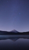 📱夜の銀河と湖に鏡面する山 iPhone 14 Plus 壁紙・待ち受け