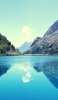 📱澄んだ青空と緑残る岩山と綺麗な湖 iPhone 14 壁紙・待ち受け