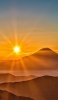 📱山の後ろで光る太陽 iPhone 12 Pro Max 壁紙・待ち受け