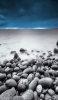 📱沢山の丸い石と靄がかった砂浜 iPhone XR 壁紙・待ち受け