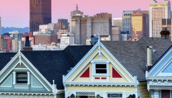 📱立ち並ぶ白い住宅地 遠くに見える高層ビル ピンクのグラデーションの空 AQUOS wish 壁紙・待ち受け